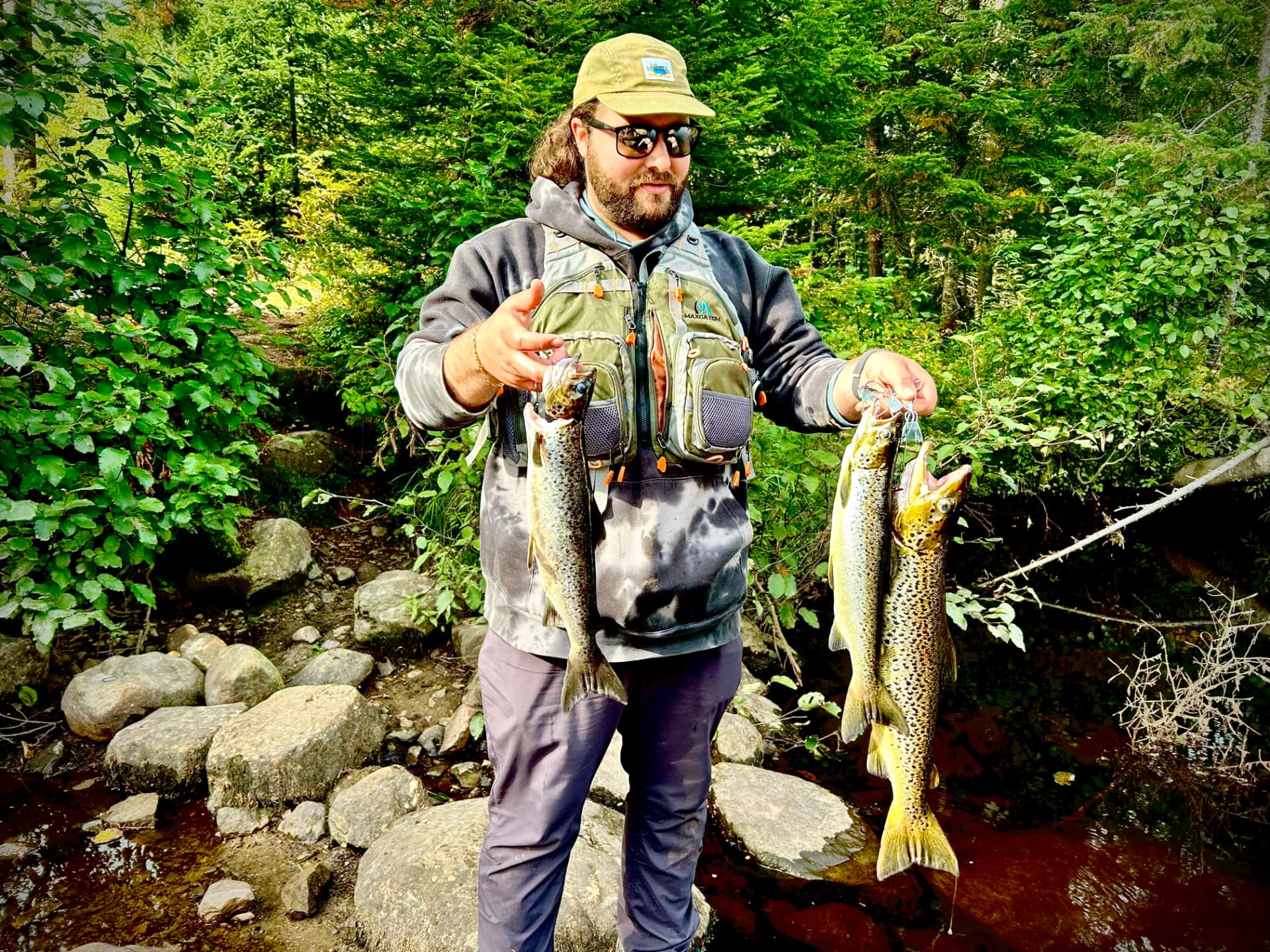 Guide de pêche tenant trois ouananiches sur la rive d’une rivière près de Mont-Tremblant