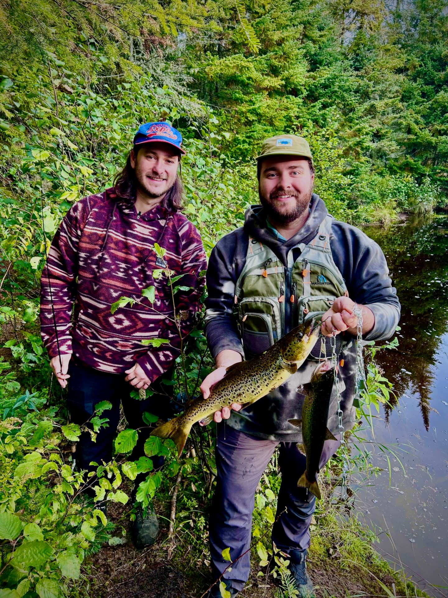 Deux pêcheurs souriants présentant des ouananiches au bord d’une rivière près de Mont-Tremblant