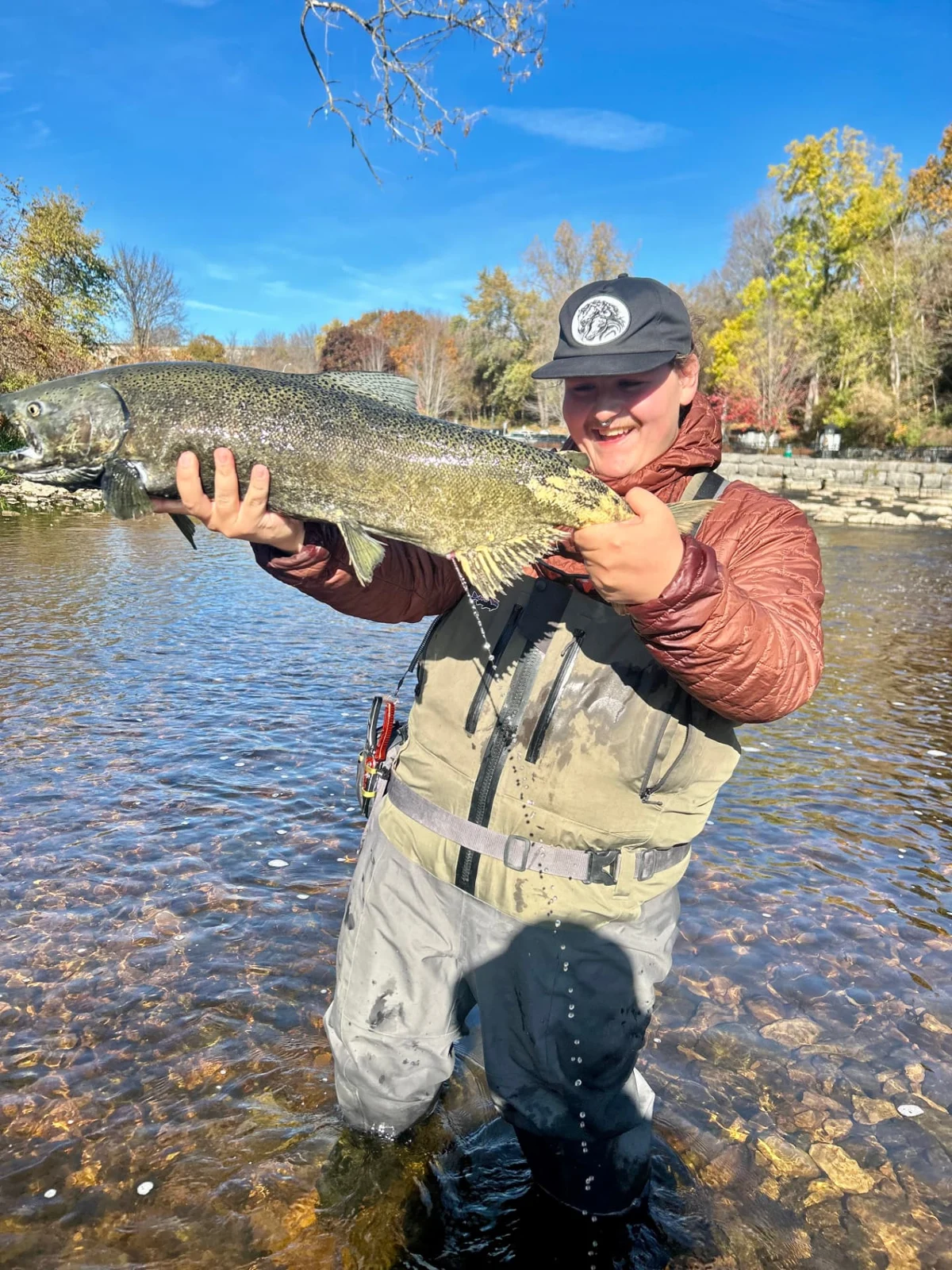 A smiling angler holding a Chinook salmon in Kingston.
